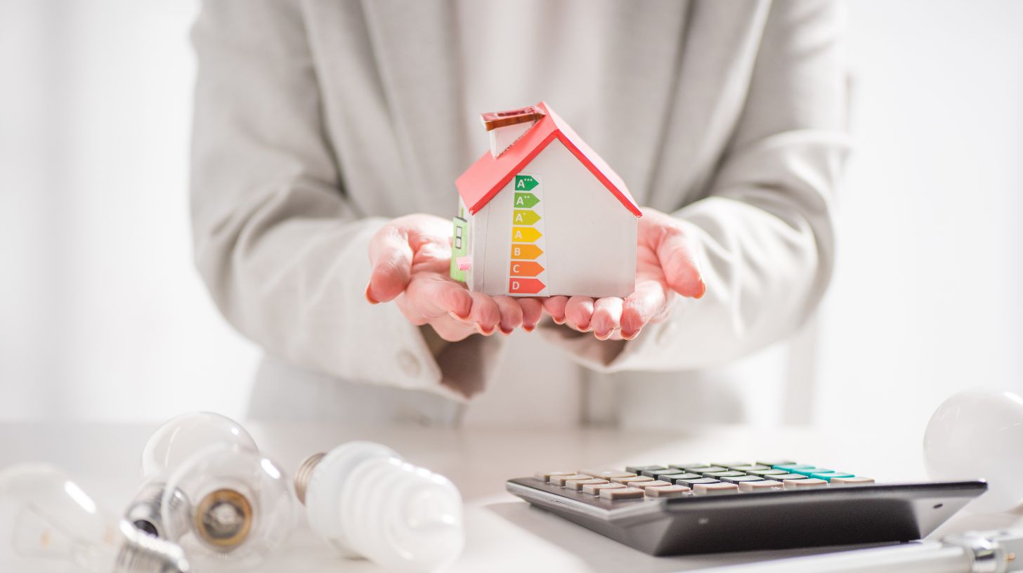 a woman holding a cardboard house with energy symbols